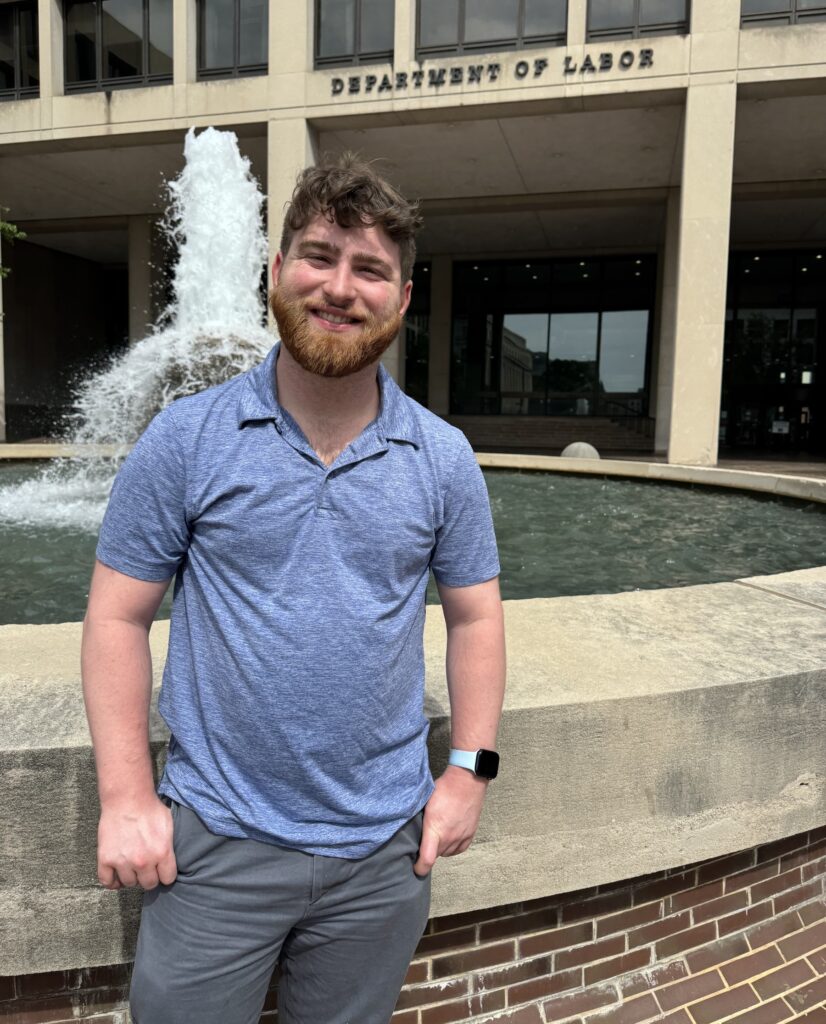 Adam Fishbein posing for a photo in front of a fountain at the Department of Labor building