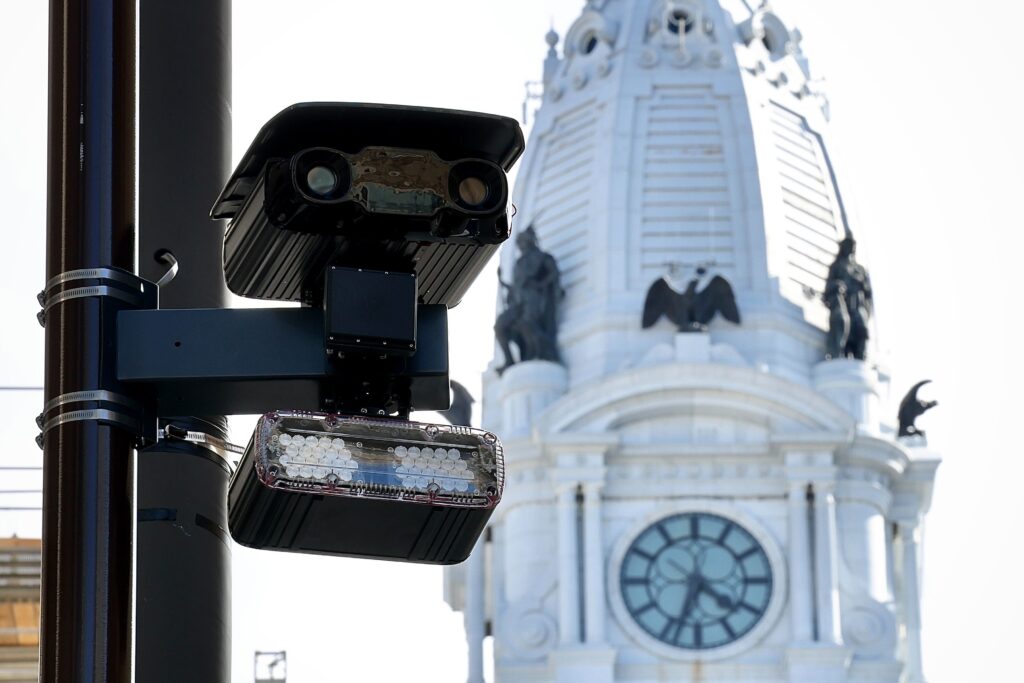 broad-street-speed-camera-e-lee-2025-08-19 Close-up shot of a speed camera attached to a light pole, with City Hall in the background
