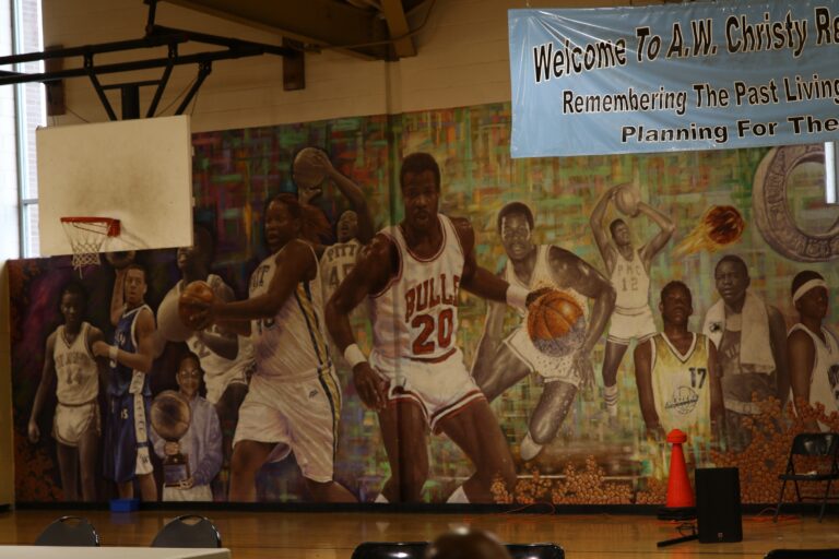 a wall with a mural of multiple people inside the basketball gym at Christy Rec Center