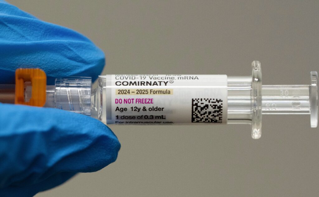 covid-vaccine-file-2025-ap A pharmacist holds a Pfizer and BioNTech COVID-19 vaccine shot