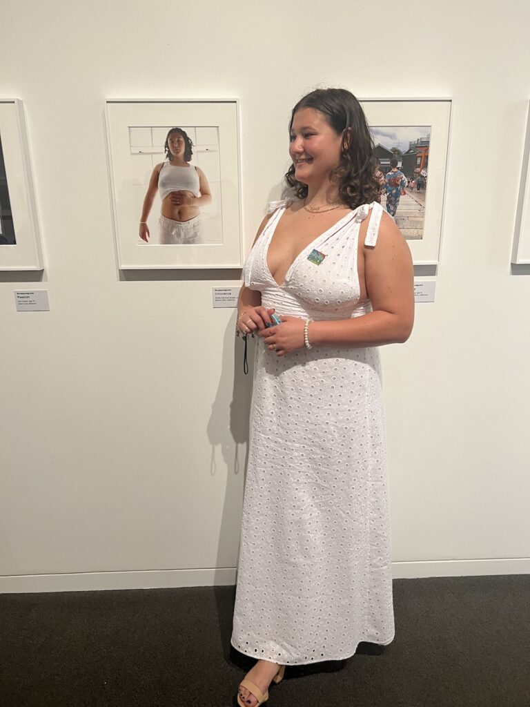Elodie Hekimian-Brogan stands by a photographed self-portrait titled "Reconnecting With Innocence" at a reception at the Getty Villa Museum in Los Angeles. Her photograph was displayed at the art museum in 2022 for six months. (Courtesy of Elodie Hekimian-Brogan)
