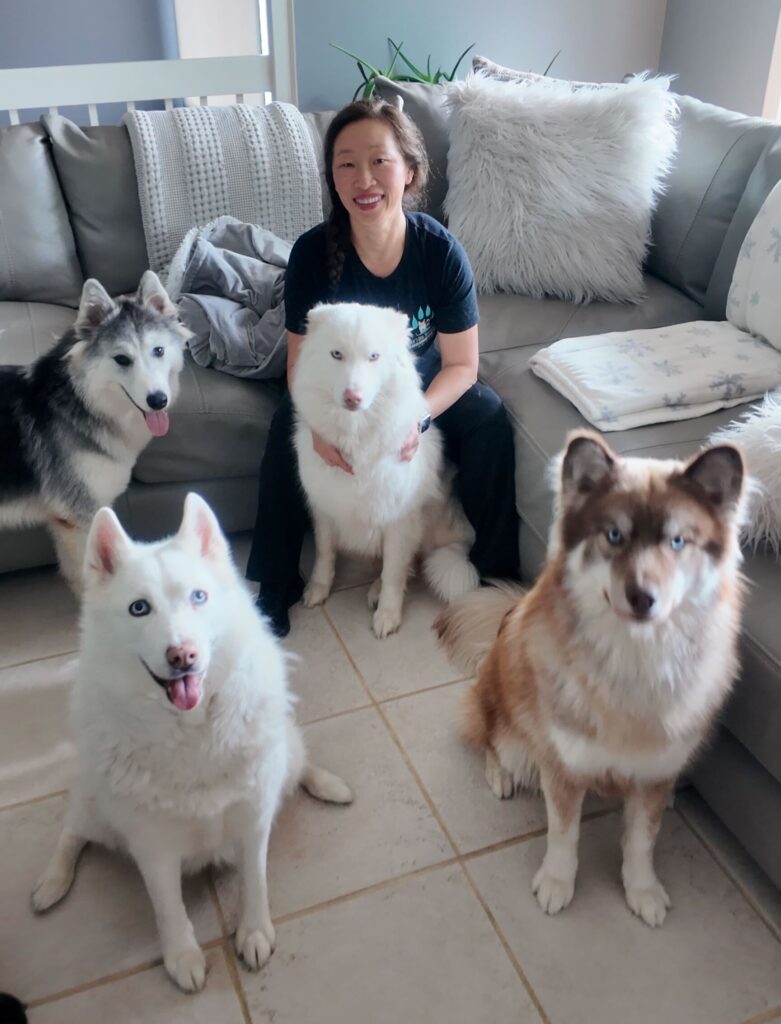 A woman posing for a photo in her home with several dogs