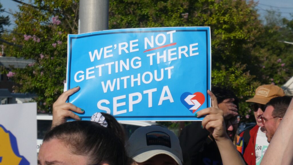 a sign reads WE'RE NOT GETTING THERE WITHOUT SEPTA