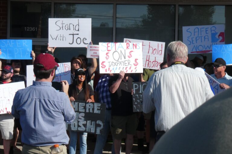 Supporters of Picozzi hold signs outside his office