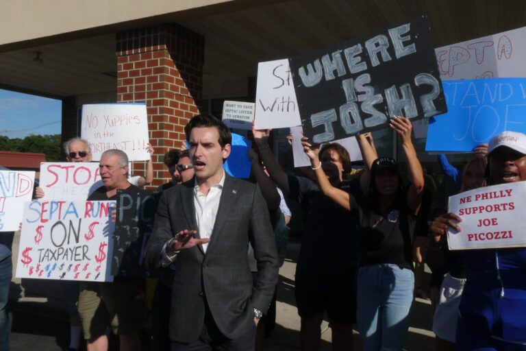 Joe Picozzi speaks, with supporters holding signs behind him