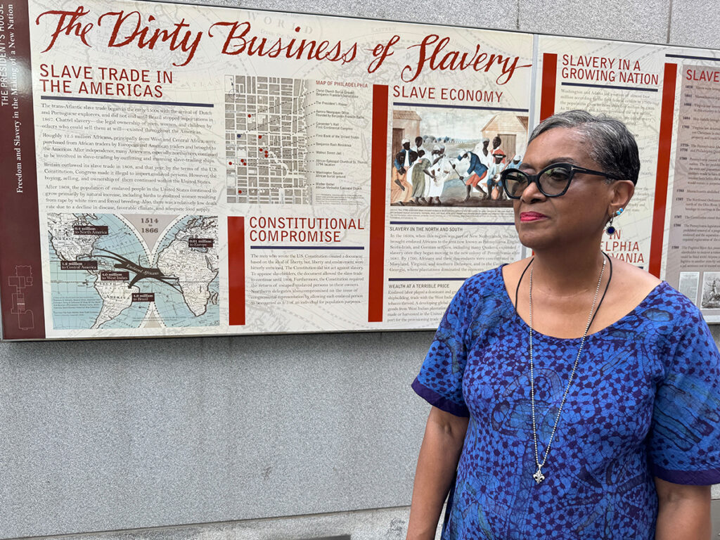 president_house_site_protest5_08022025 Roz McPherson stands in front of a panel exhibit about slavery