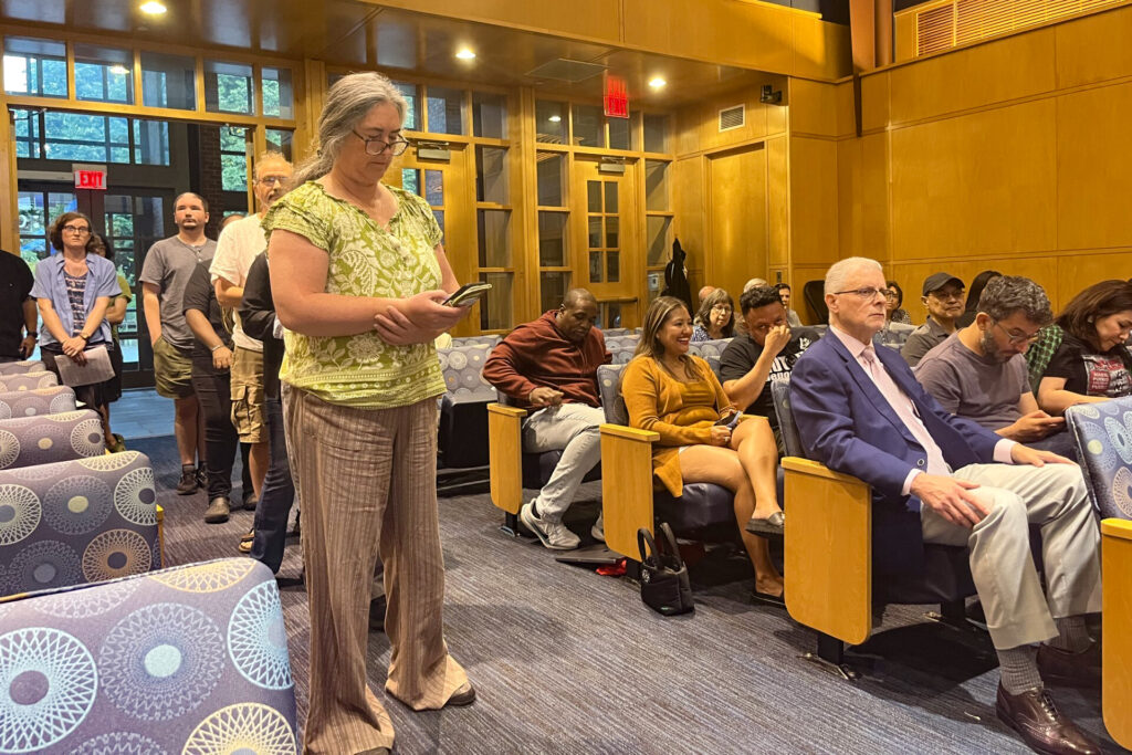 princeton-2025-08-12-1 A woman speaks at a podium during the meeting, with other people lining up behind her for their turn.