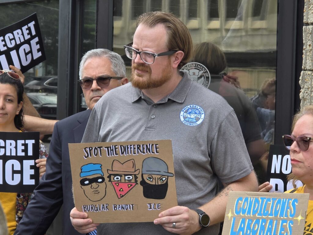 secret-police-ice-rally-philadelphia-2025-08-14-2 Danny Bauder holds a sign criticizing ICE agents for wearing masks