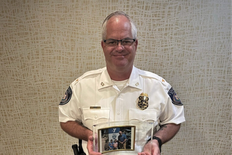 Michael Trail posing with a photo of himself with some children