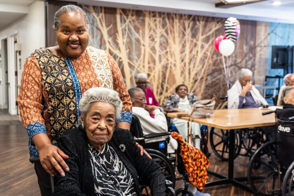 09-22-2025-k-paynter-Centenarian-Day-at-the-simpson-house-10 A woman standing behind her elderly aunt who is sitting in a wheelchair