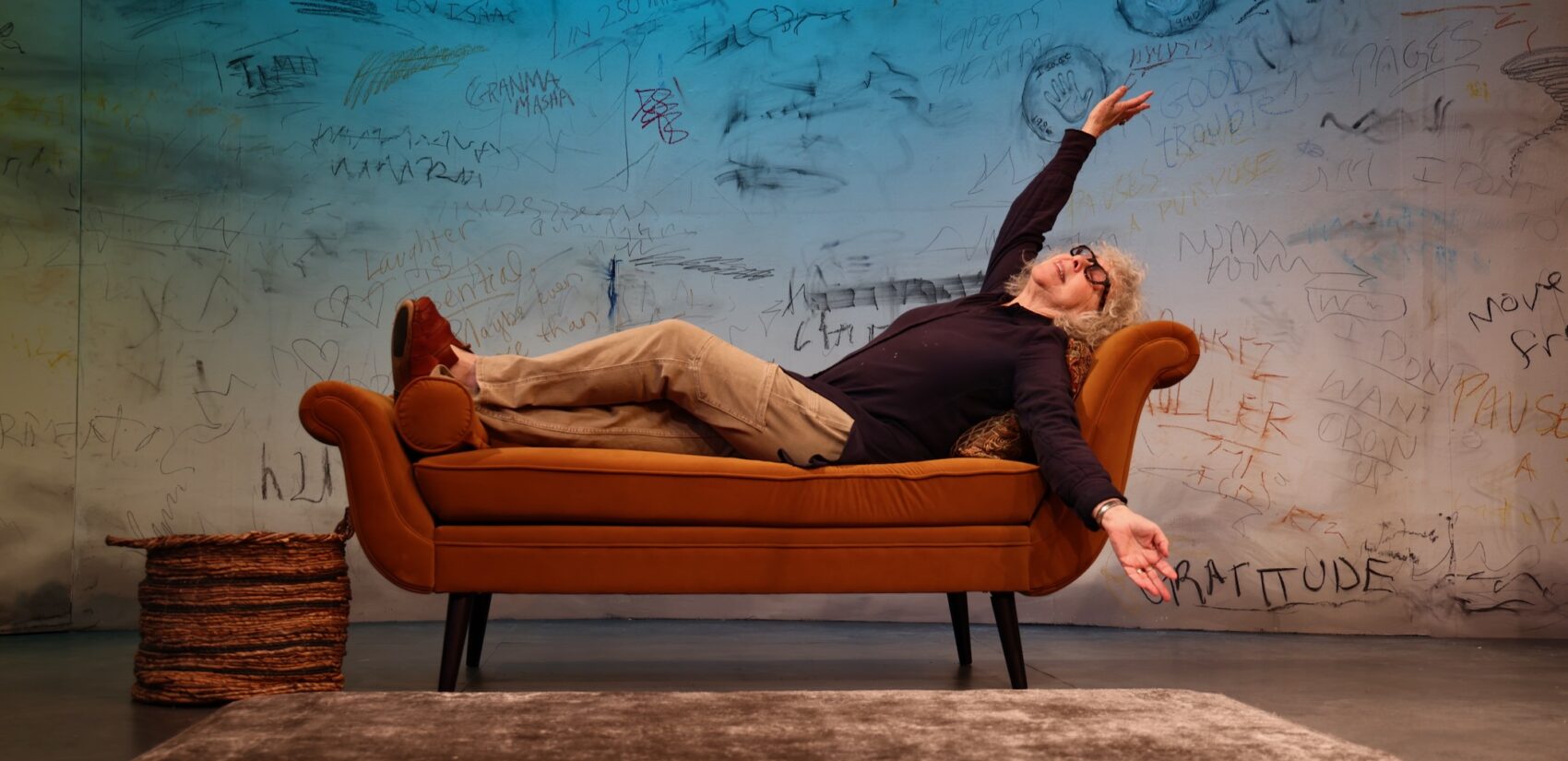Kathryn Grody horizontal on a couch on stage
