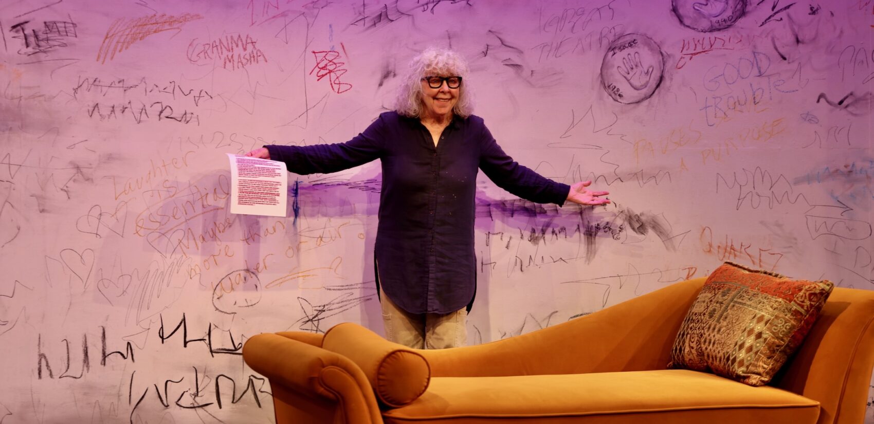 Kathryn Grody holds a page of the script for her one-woman show on stage