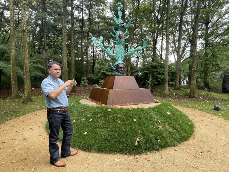 Salvador Jiménez-Flores poses for a photo near his sculpture