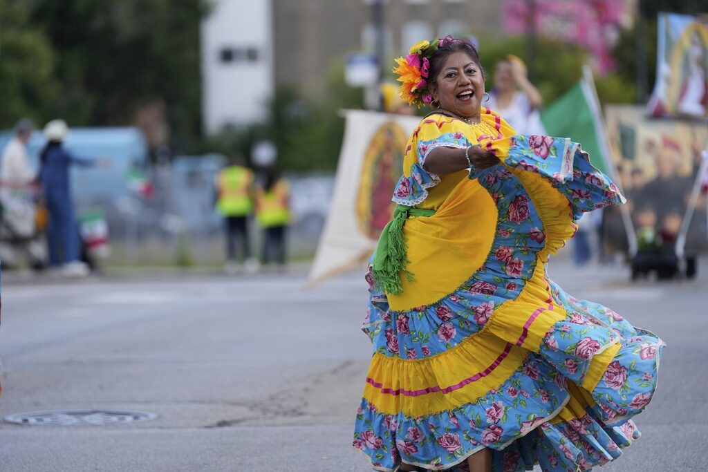 A woman dances in a blue and yellow dress during a Mexican Independence Day parade in Chicago