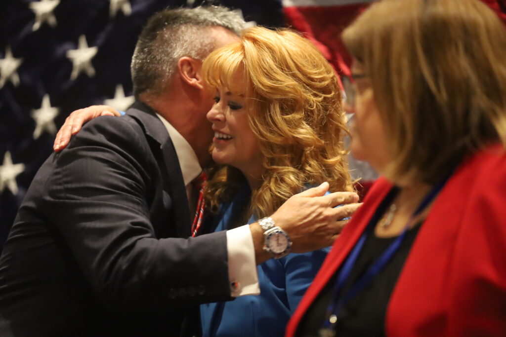 State treasurer Stacy Garrity hugs party chair state Sen. Greg Rothman