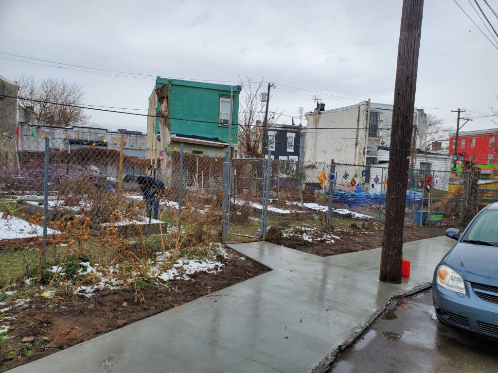 A sidewalk goes in front of a community garden