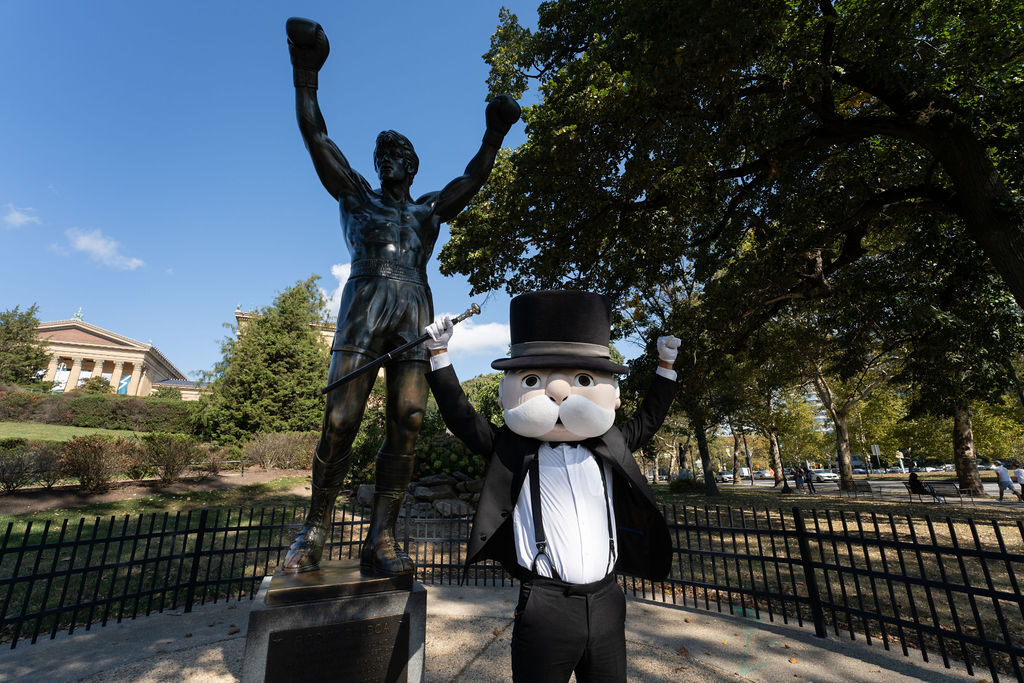 Mr. Monopoly posing with the Rocky statue