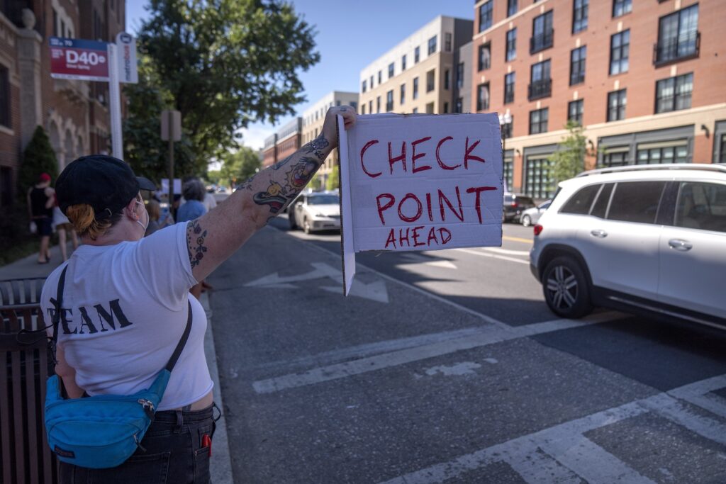 People hold signs warning drivers of a checkpoint 