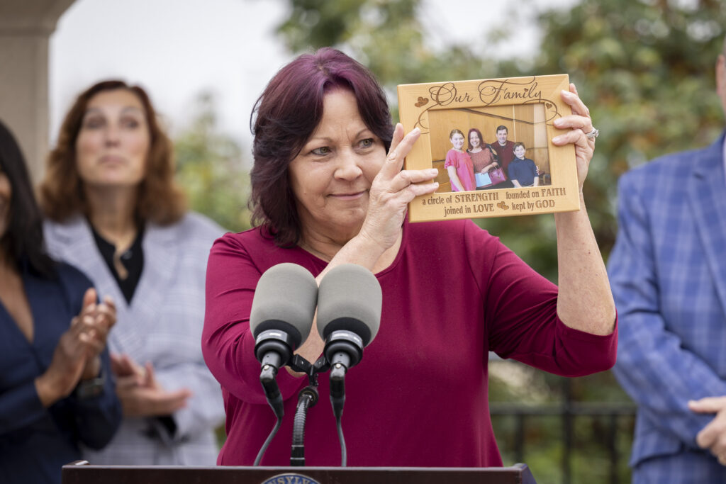 grandparents-hotline-pa-2025-09-25 A woman holds up a framed photo of her family