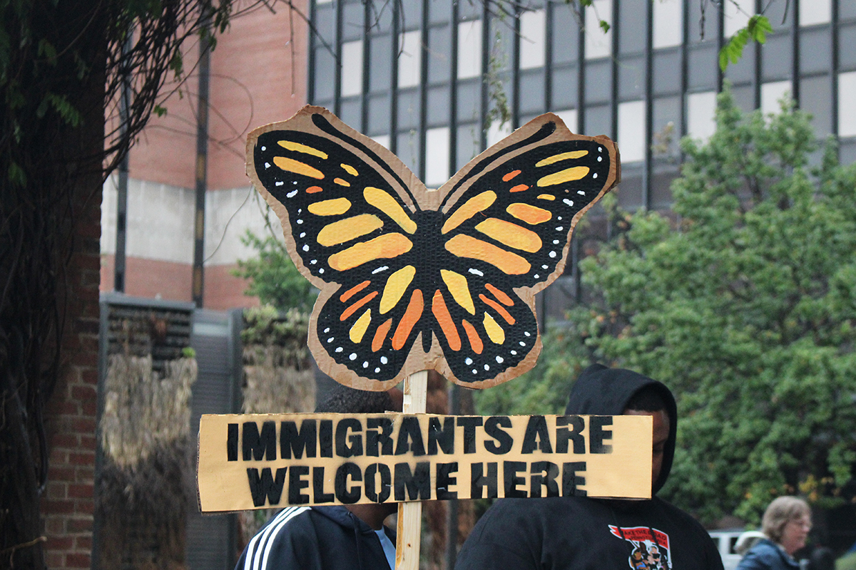 a sign at an immigrant rights rally in Philadelphia shows a butterfly and reads IMMIGRANTS ARE WELCOME HERE
