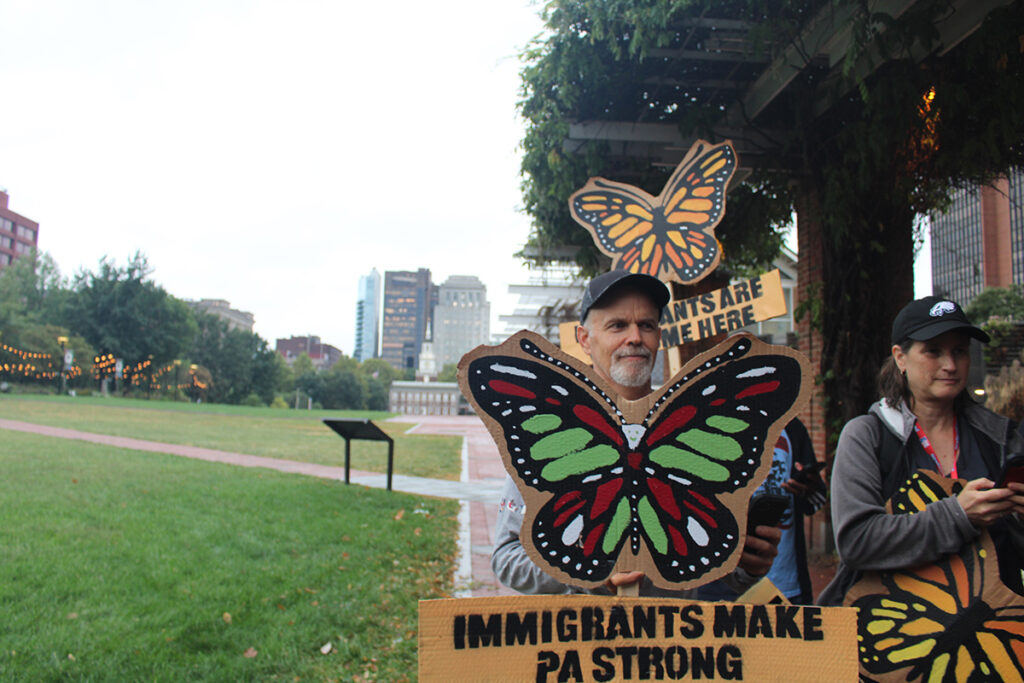 Immigrant advocates hold signs at a rally in Philadelphia