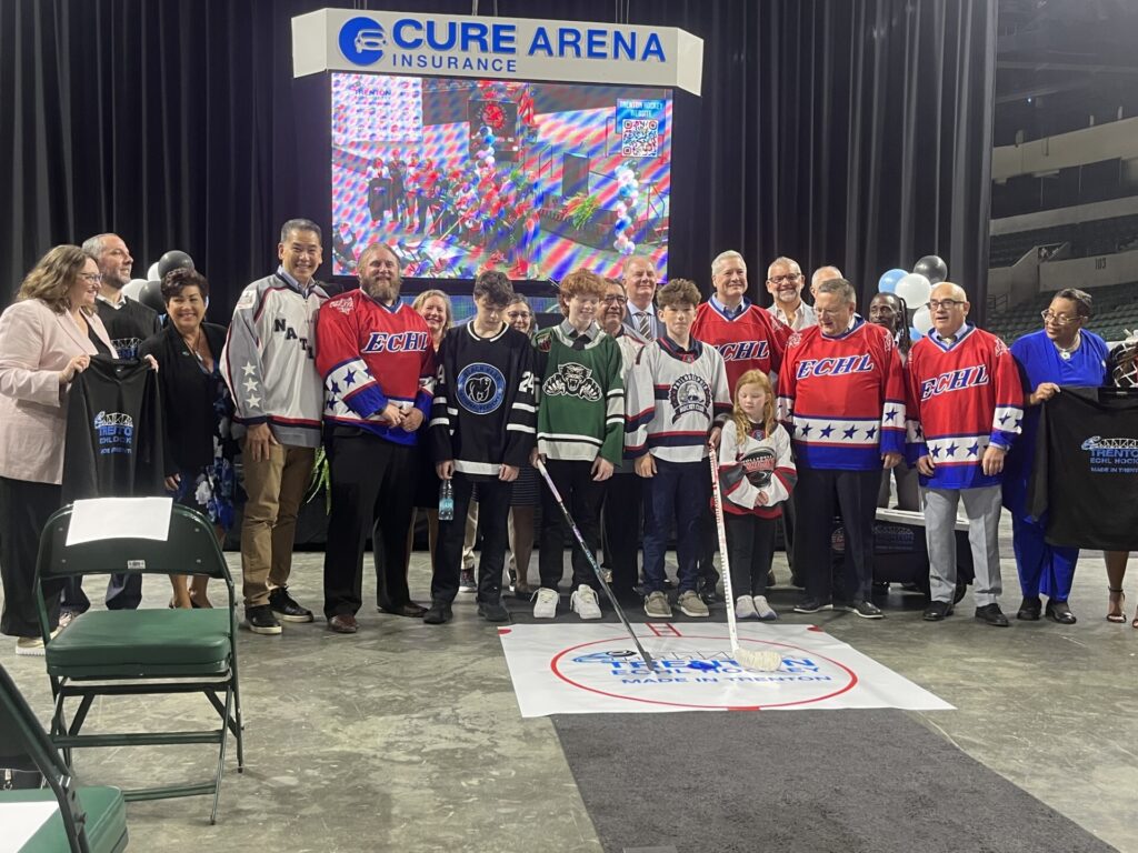 mercer 1 Officials posingwith youth hockey players wearing their jerseys and holding hockey sticks