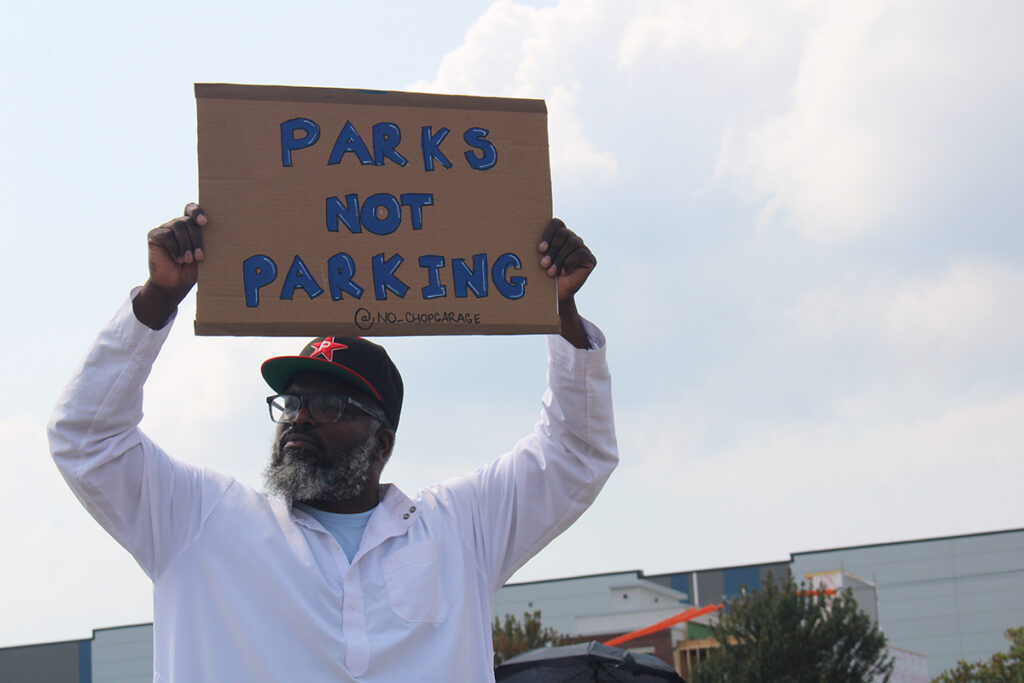A man protesting a proposed Children's Hospital of Philadelphia parking lot holds a sign that reads 