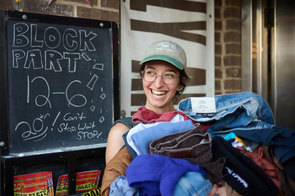 philadelphia-aids-thrift-block-party-2025-09-13 A happy shopper shows off her haul at the 20th anniversary Philly AIDS Thrift block party