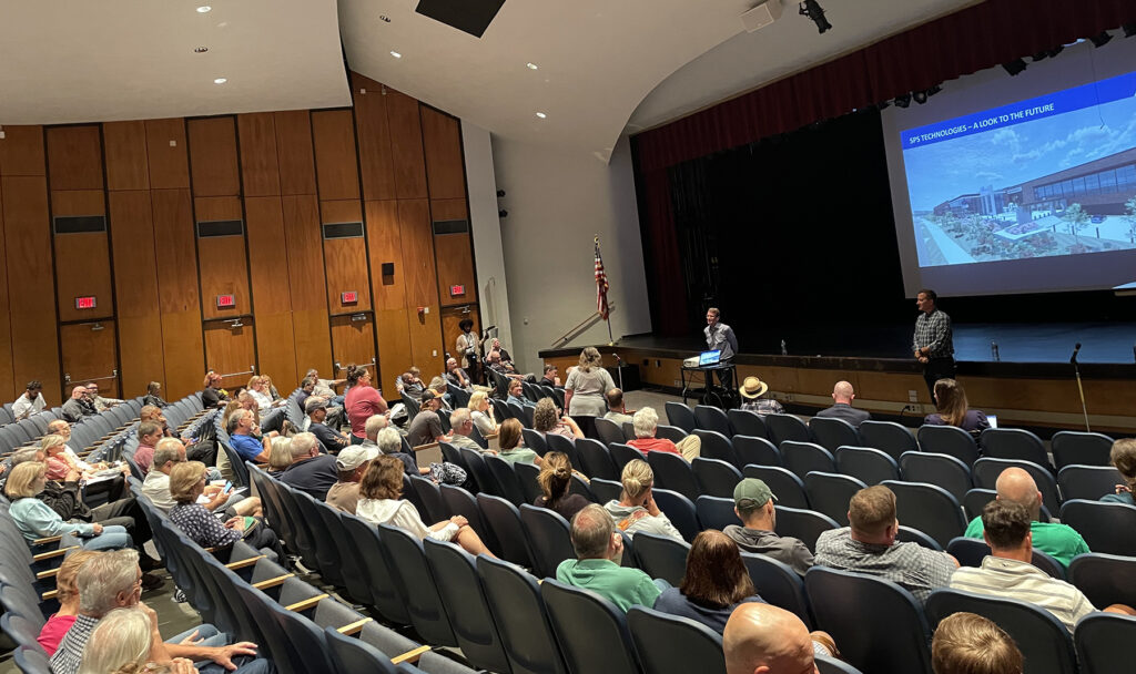 Representatives from SPS Technologies speak to members of the Abington community inside an auditorium.