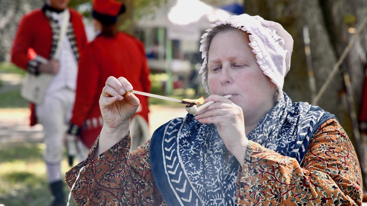 Camp follower lights her pipe during a reenactment
