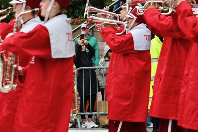 A spectator photographs the Temple University marching band