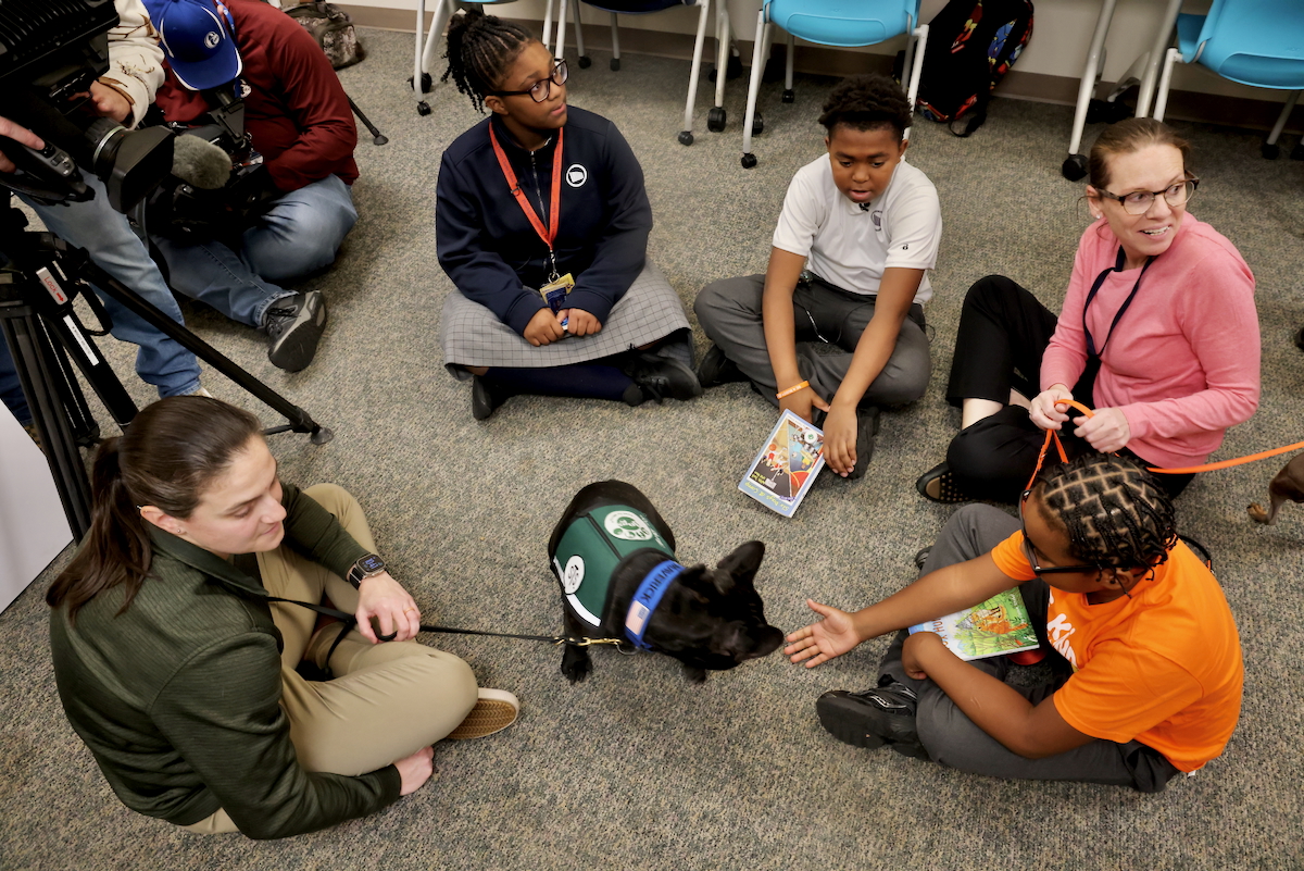 students sitting with String Theory School staff and therapy dogs