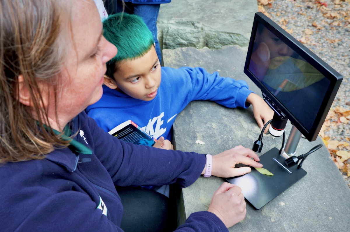 Beth Clark and Nicholas Herron use a digital microscope to examine a leaf