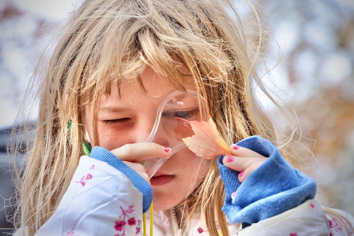 Hannah Stevenson uses a magnifying glass to inspect a leaf