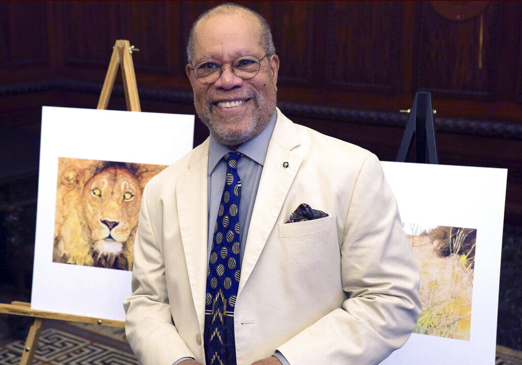 Children's book illustrator Jerry Pinkney poses in front of two of his illustrations