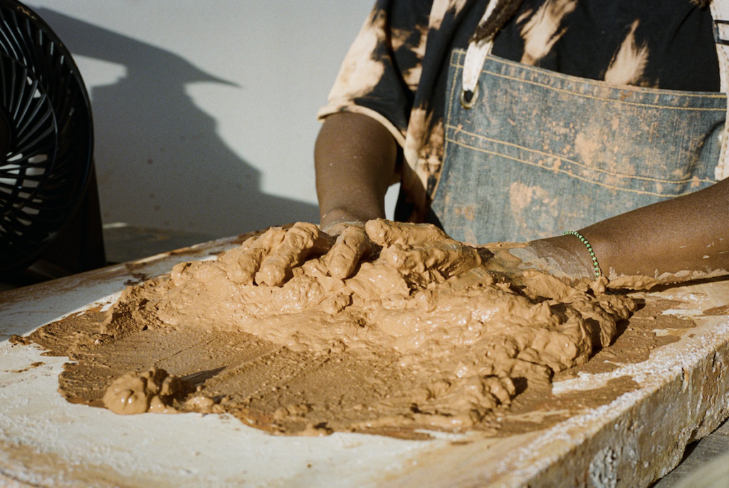 A person working with red clay on a table