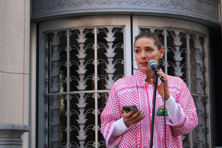 Samah Elhajibrahim, a Palestinian-American scholar, speaks into a microphone outside of Sen. John Fetterman's Old City office