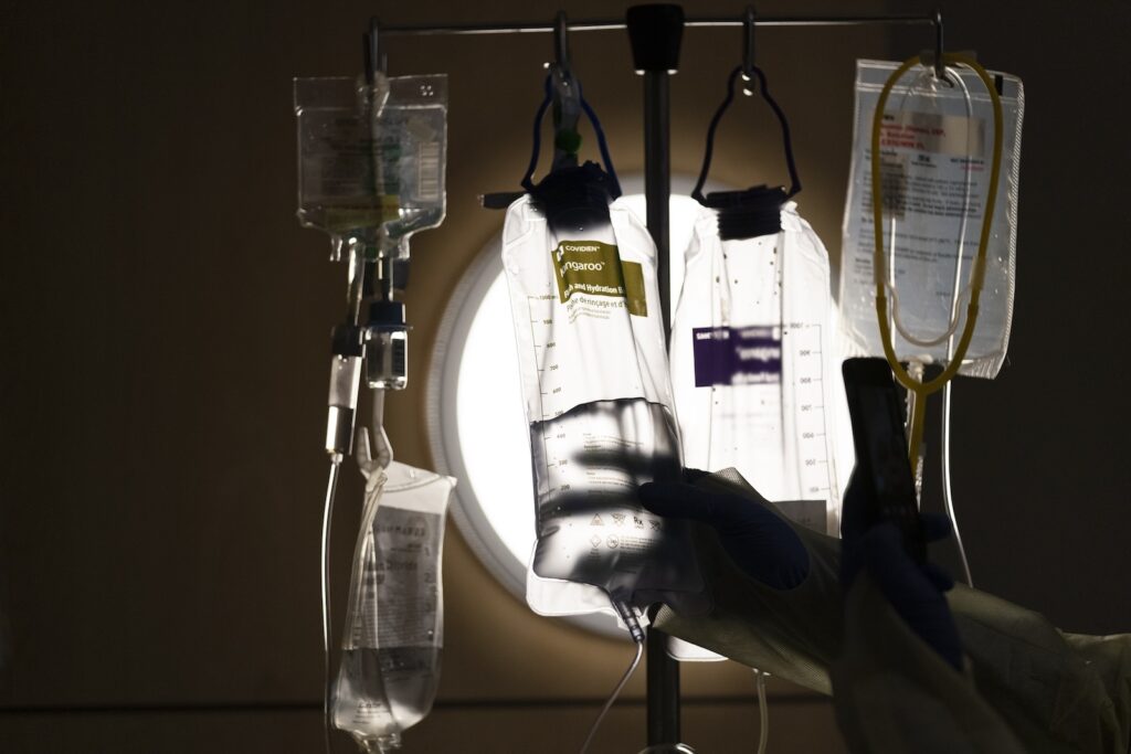 A nurse checks on IV fluids while talking to a patient.