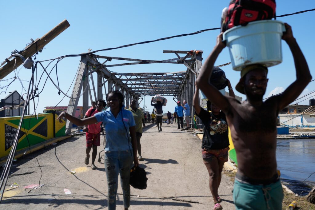 Residents leaving Black River, Jamaica with a damaged bridge behind them