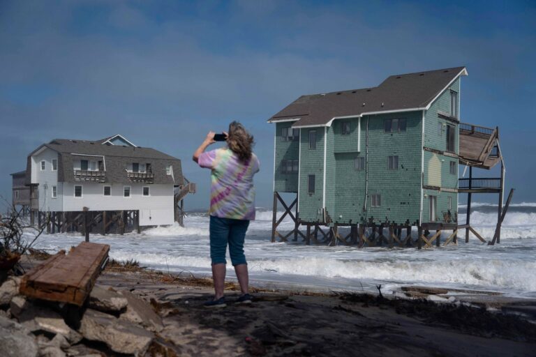 A person stands and takes photos of houses