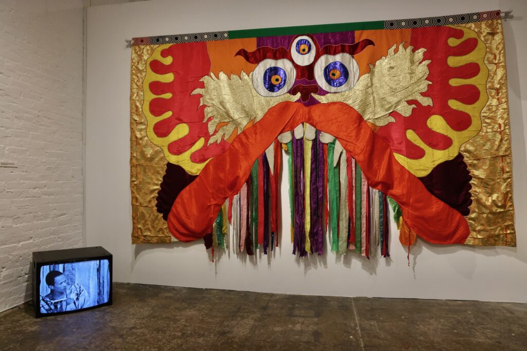 Moki Cherry's colorful tapestry is juxtaposed with a video