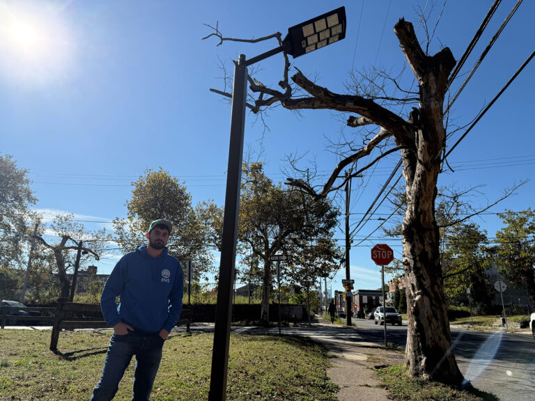 A man stands underneath a solar-powered streetlight