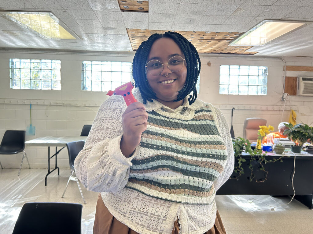 Taylor Quinland, project manager for place-based initiatives with Philadelphia's Office of Sustainability, holds a tool that can break a car window and cut a seat belt in an emergency