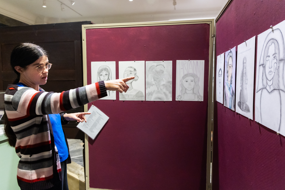 Katherine Haas pointing at images of the women of the Ospedali drawn by students at Girard College