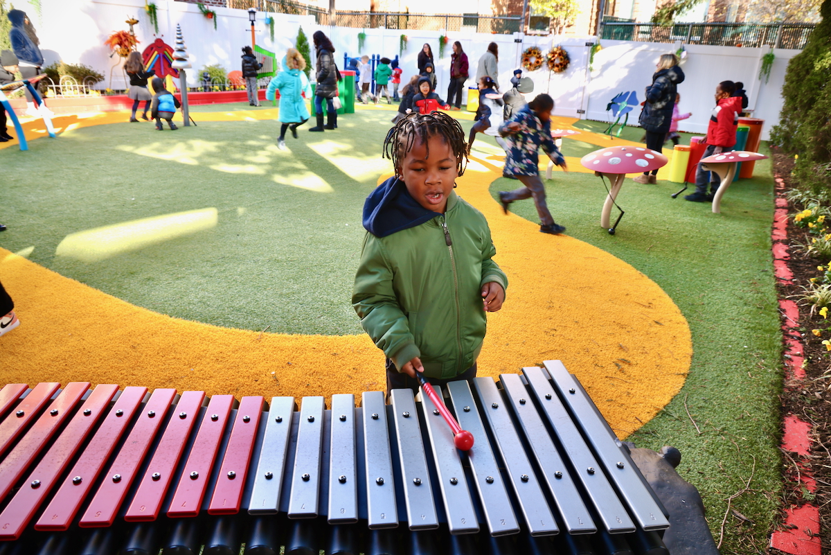 a child plays a xylophone with other children in the background
