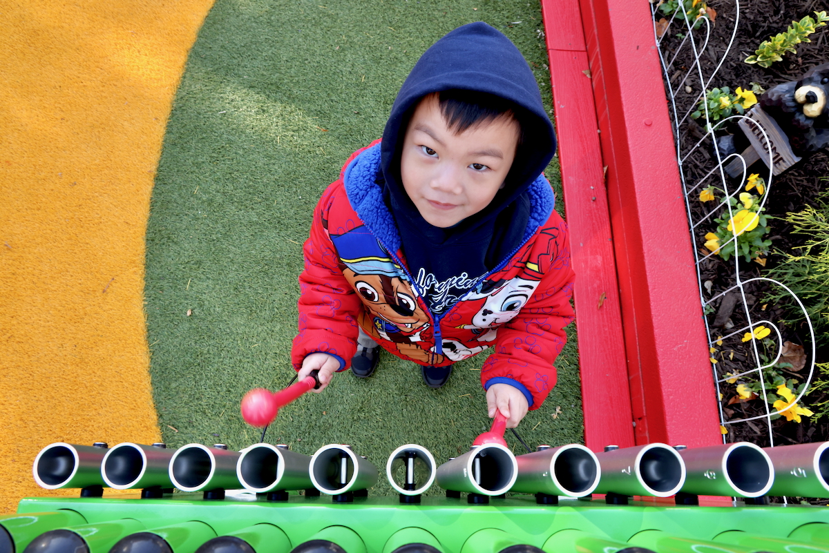 a child plays music on metal pipes