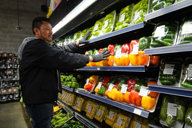 A grocery store employee stocks produce