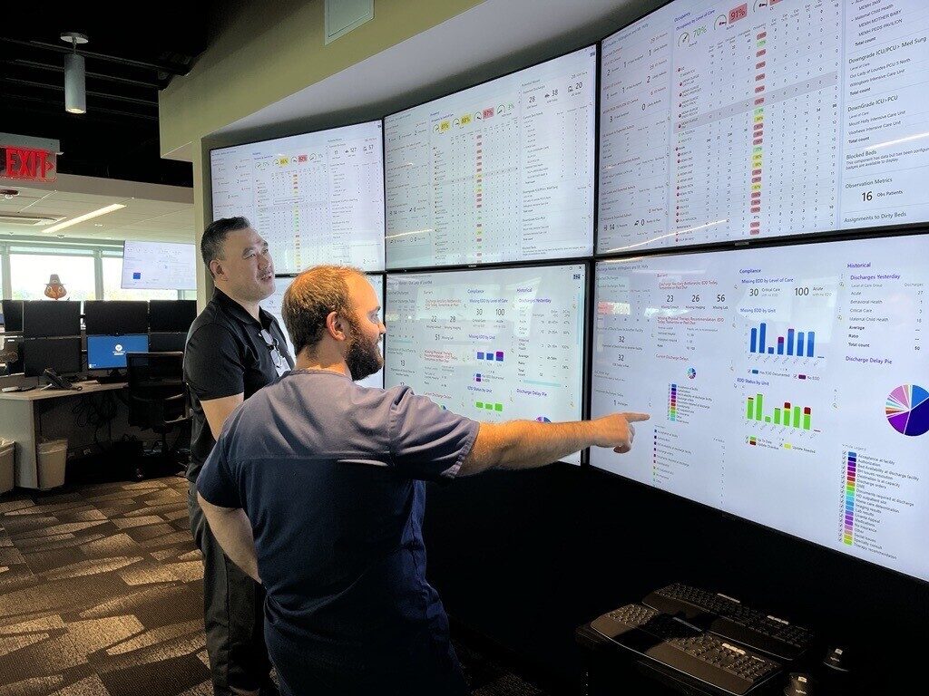 Two workers look at screens