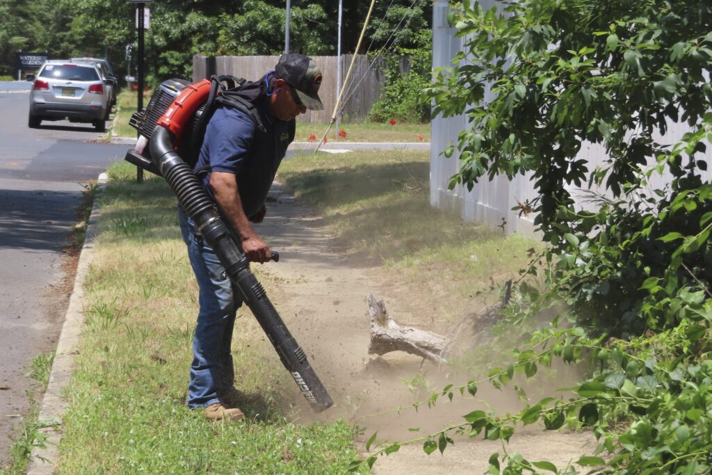 Gas-Powered Leaf Blower Bans A man using a leaf blower to clear a sidewalk