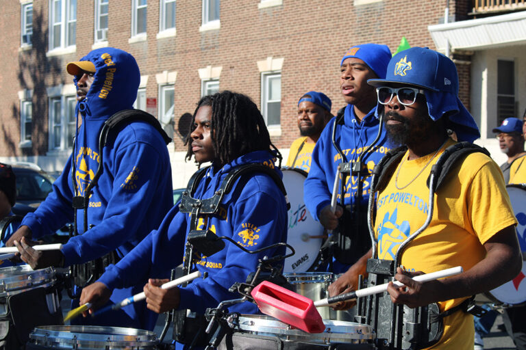 People wearing blue and yellow play the drums in the 25th annual Peoplehood Parade in West Philadelphia